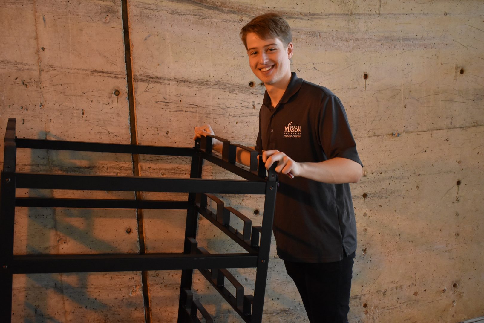 Connor taking a stack of chairs into a storage room